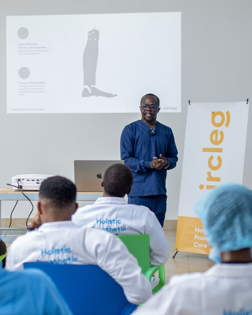 Um protésico queniano está a dar formação a um grupo de técnicos ortopédicos e protéticos africanos. Ao fundo, vê-se a prótese de perna, a «circleg».